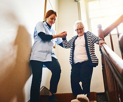 Home Care Assistant helping client down stairs