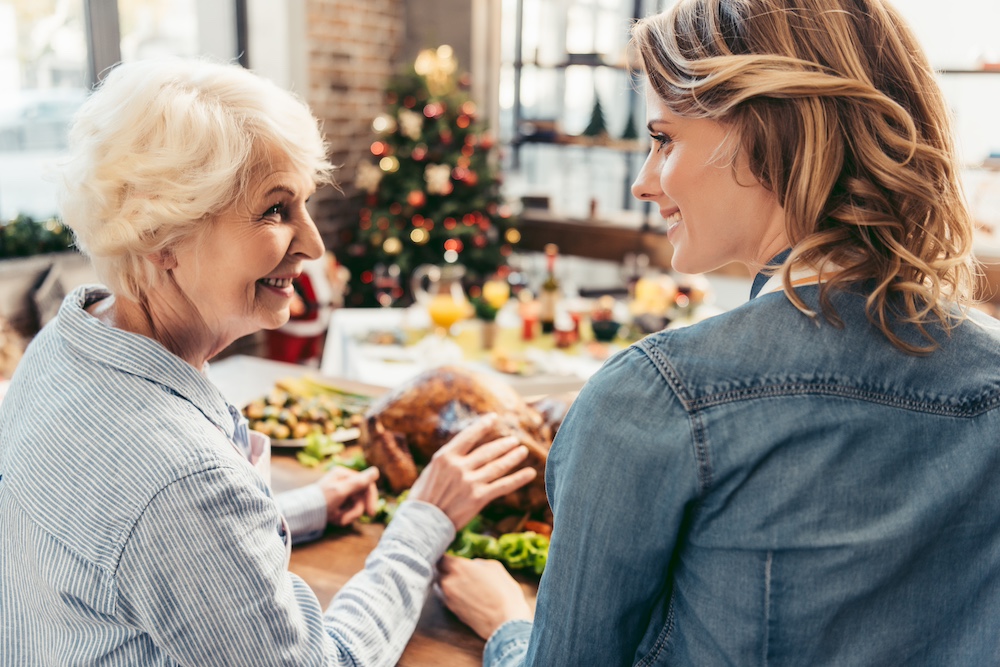 A senior woman and her daughter enjoy a holiday dinner together