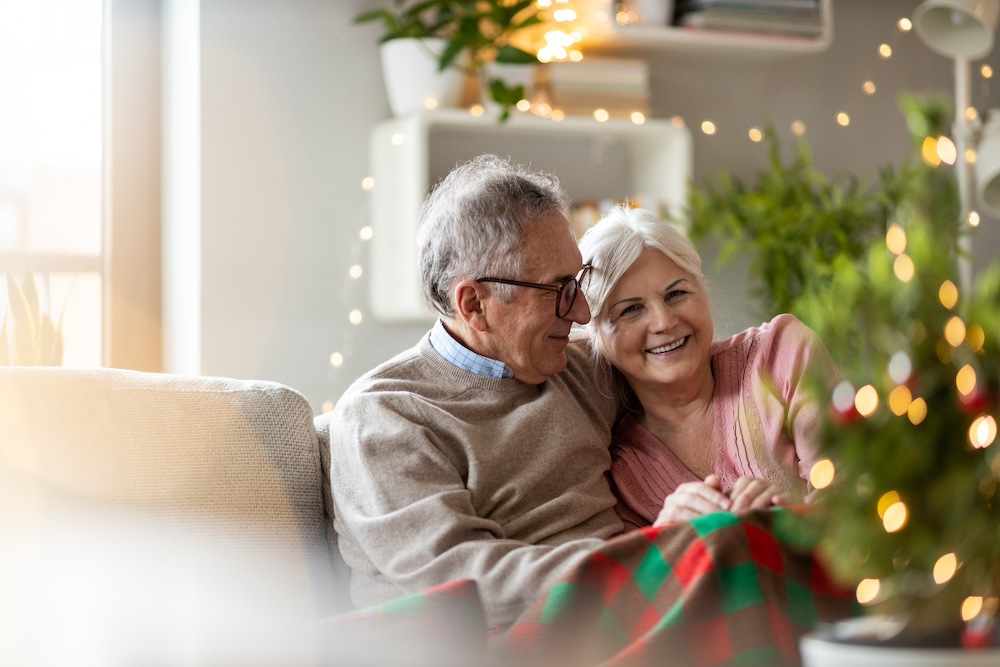 A senior couple sitting on a sofa together during the holidays. 