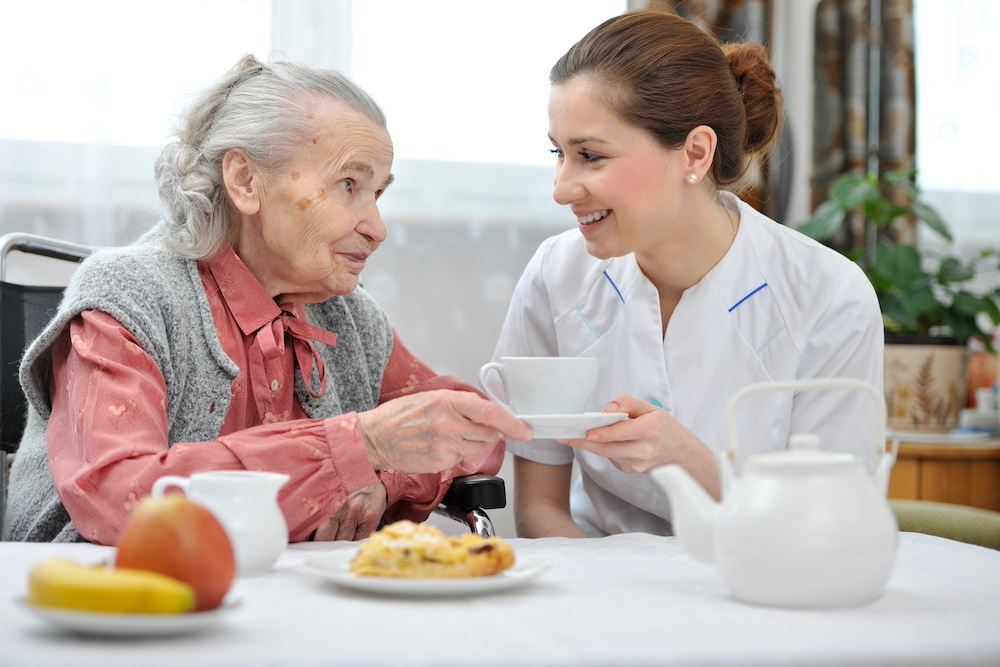 A senior woman and a caregiver having breakfast as a part of home health care services in Michigan