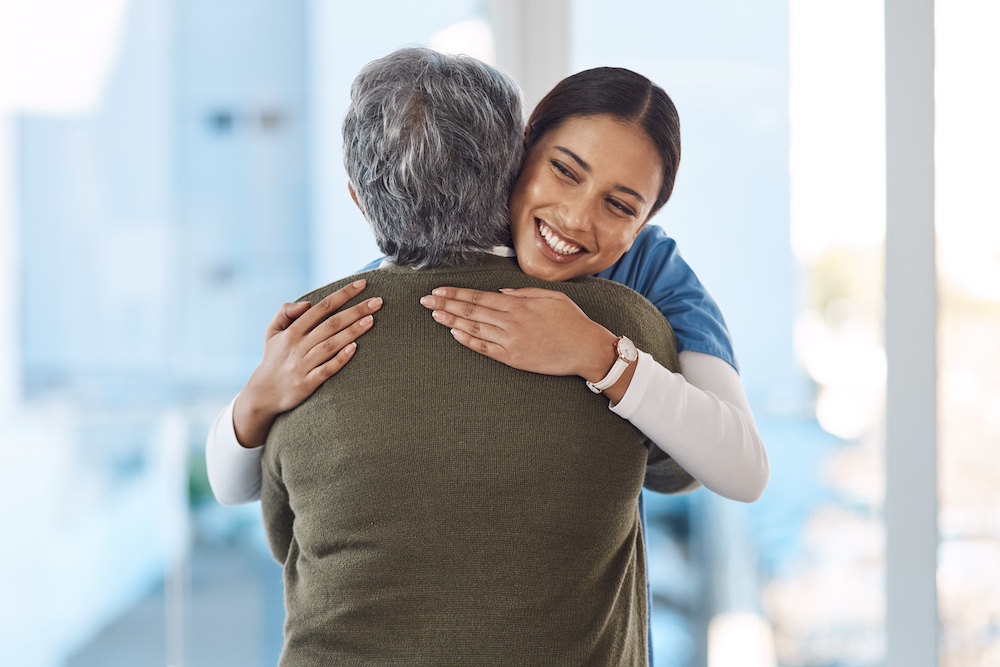 A private duty home care in Michigan caregiver hugs a senior woman