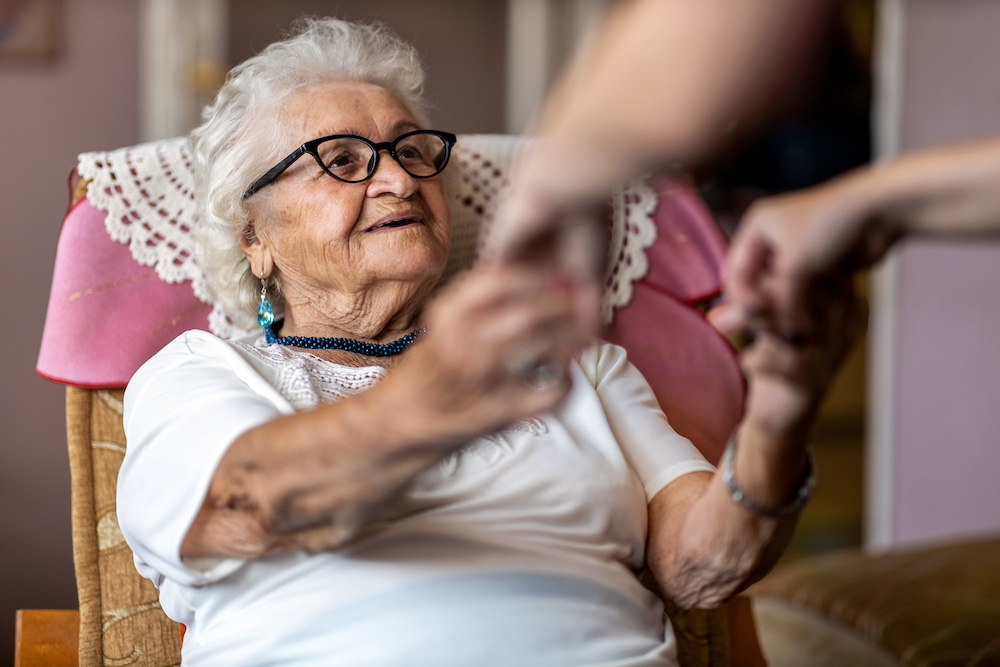 A senior woman holding hands with a caregiver