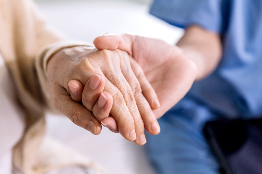 Senior holding hands with nurse in private duty home care in Northville, MI.