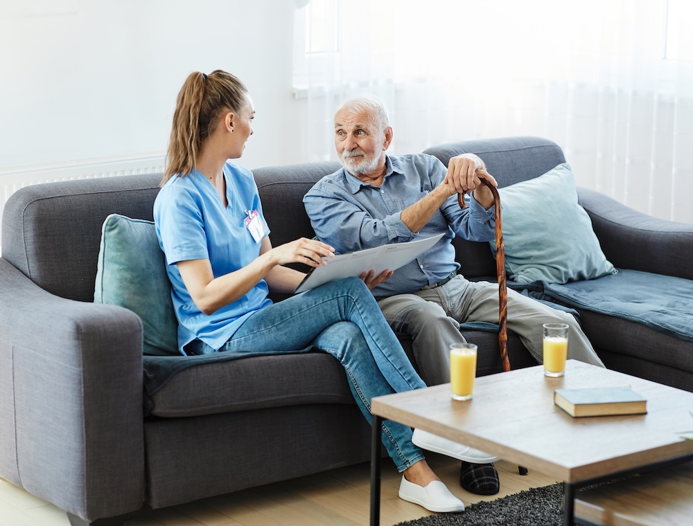 Senior with caregiver on couch talking about home health care